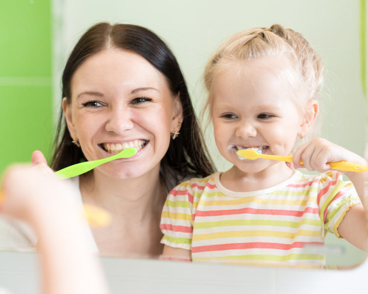 woman and child cleaning teeth
